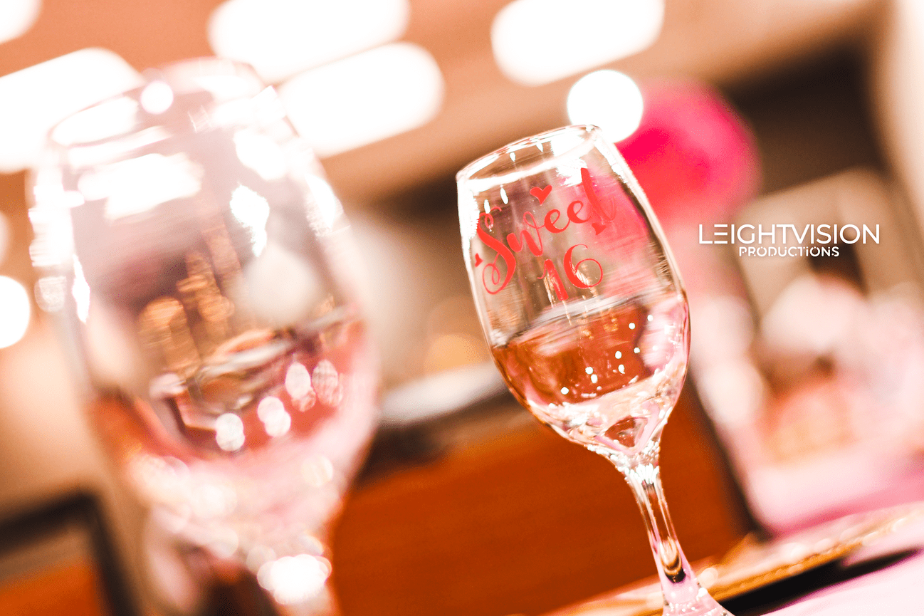Two wine glasses with decorative pink and white lettering, perfect for a celebratory occasion or gathering.