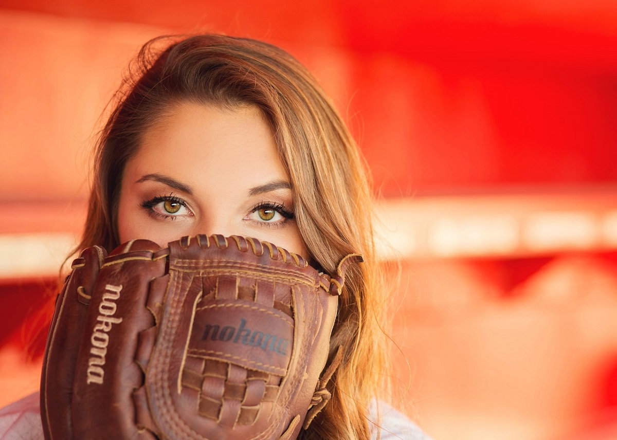High school senior girl with softball glove on red
