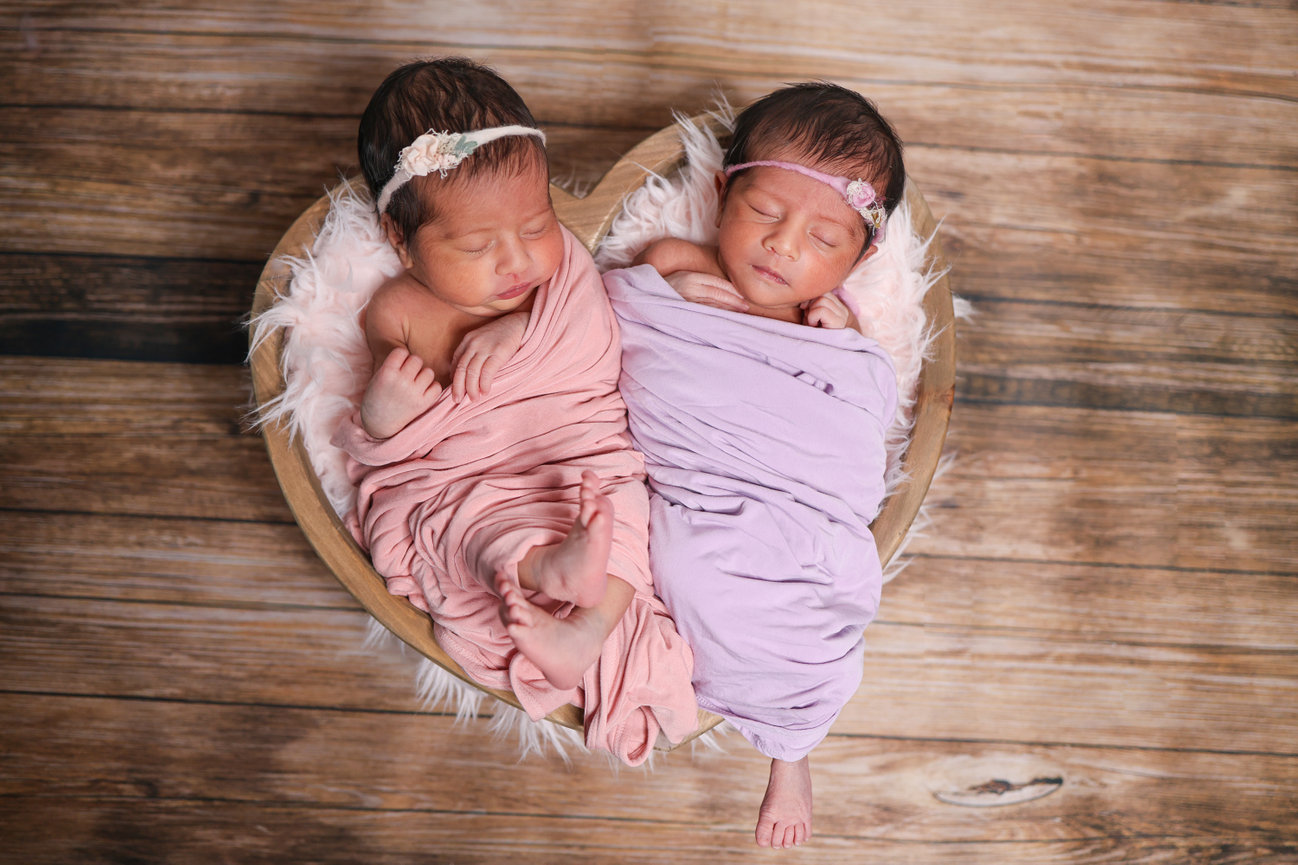 Twin newborn babies swaddled in pink and lavender blankets