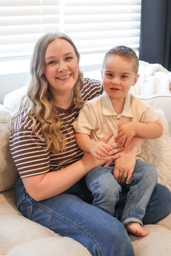 Smiling mother holding her toddler on a couch