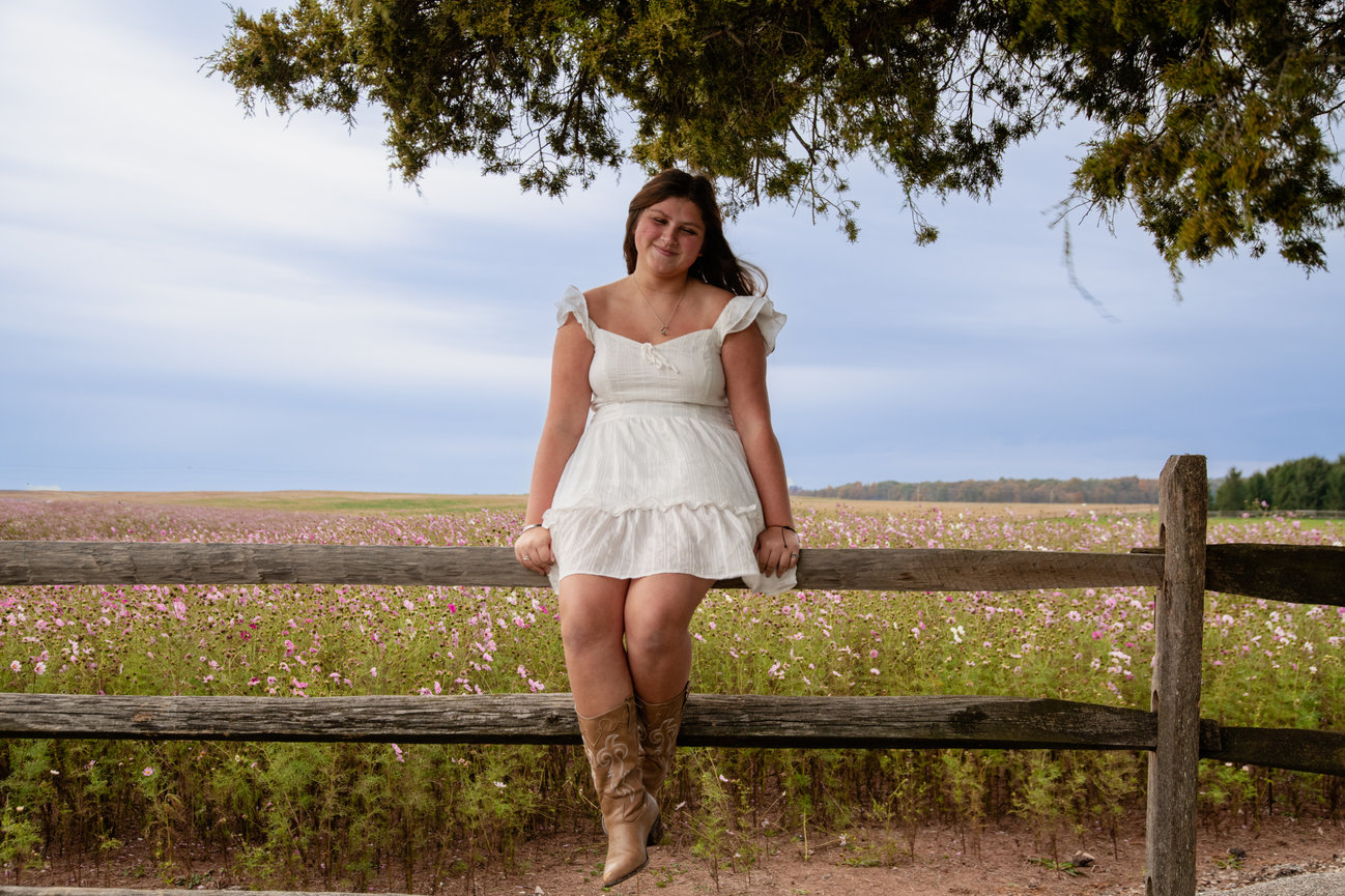 Woman in a white dress sitting on a fence