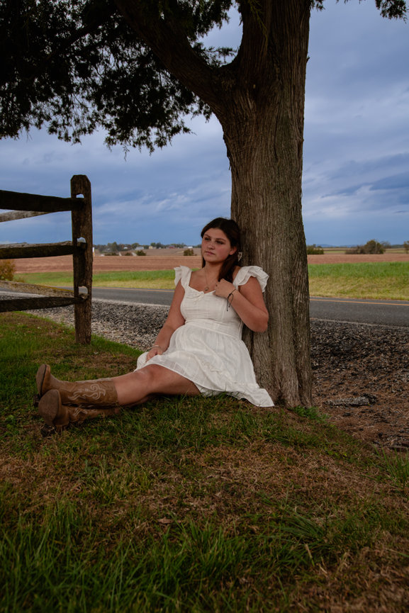 Woman in a white dress sitting on a fence