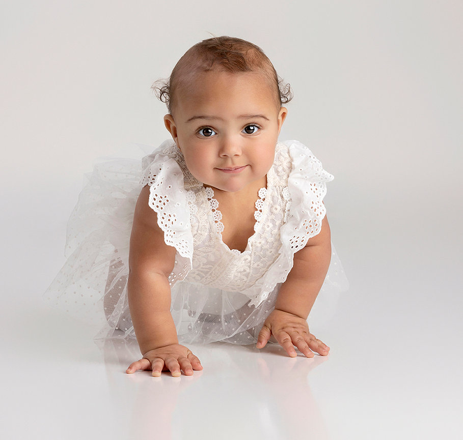 Baby crawling on a white background in a ruffled outfit