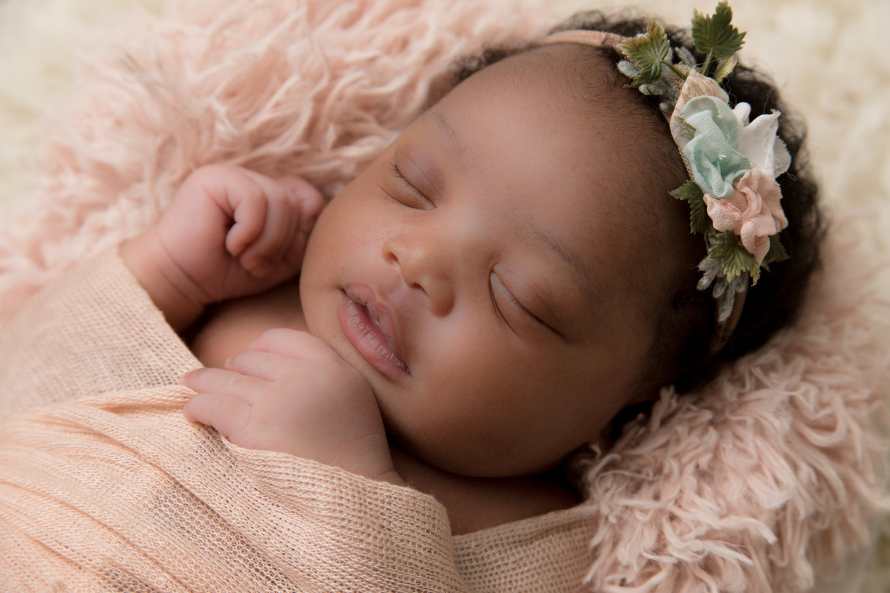 Sleeping newborn baby resting on a soft pink blanket