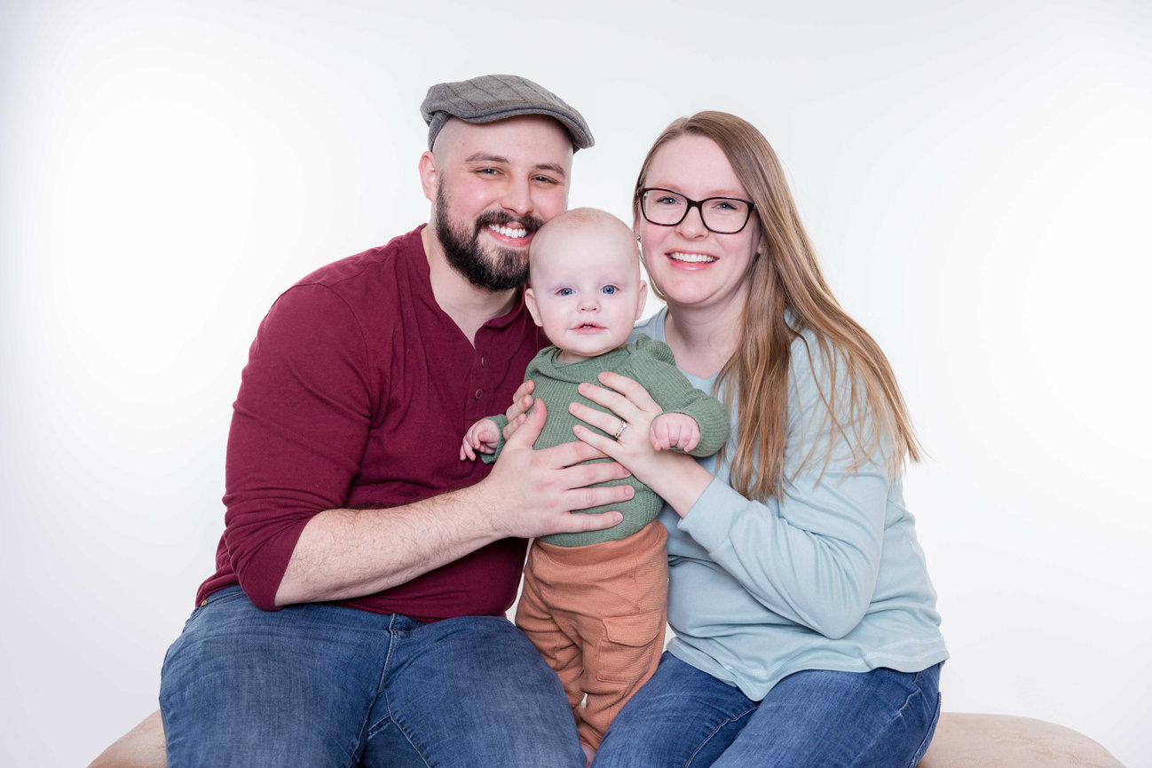 Smiling parents holding their baby in a studio family portrait in Blue Springs photographed by Case Studios Photography