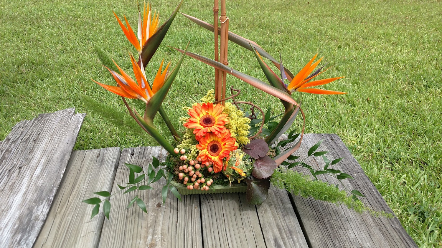 Orange floral arrangement on a wooden bench
