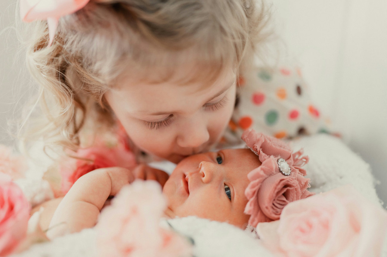 Young child kissing a newborn baby