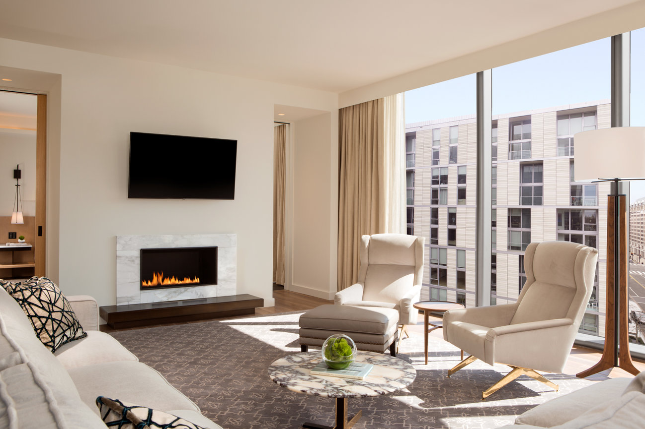 Guest room at the conrad showcasing fireplace hand selected white modern furniture with views of the city.