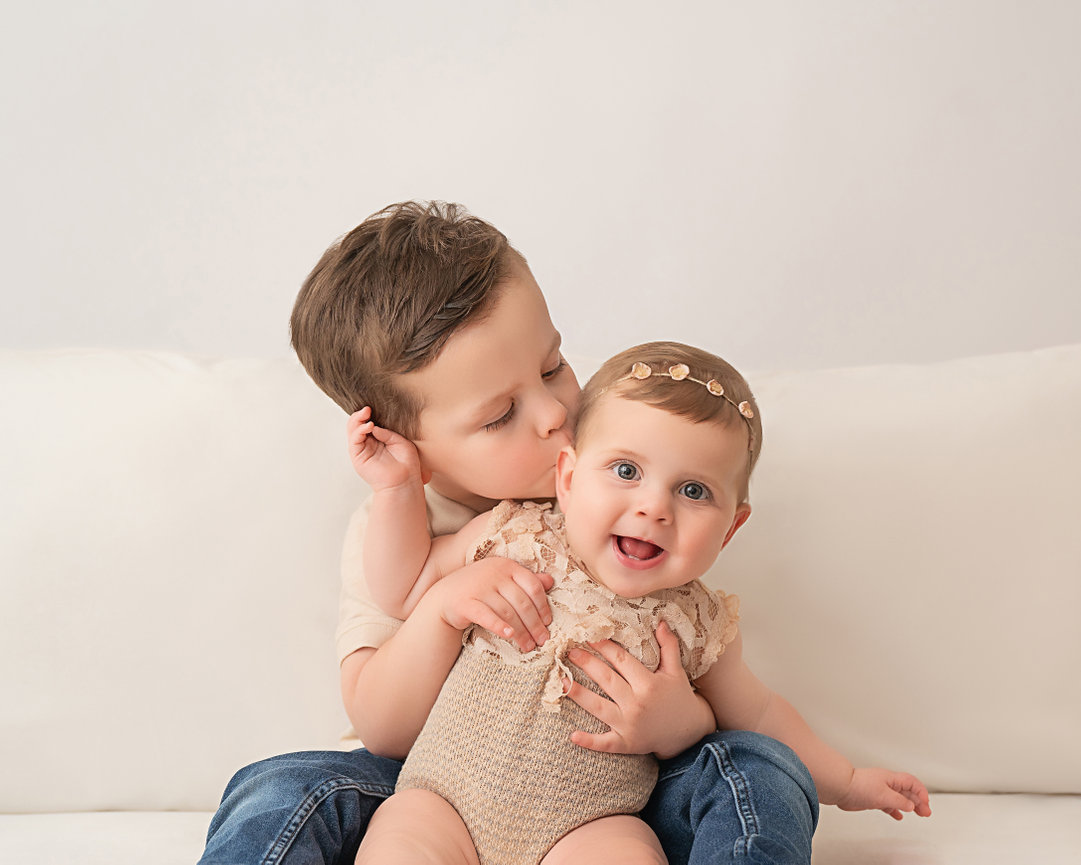 Young siblings cuddling on couch in light-filled Sea Girt studio session