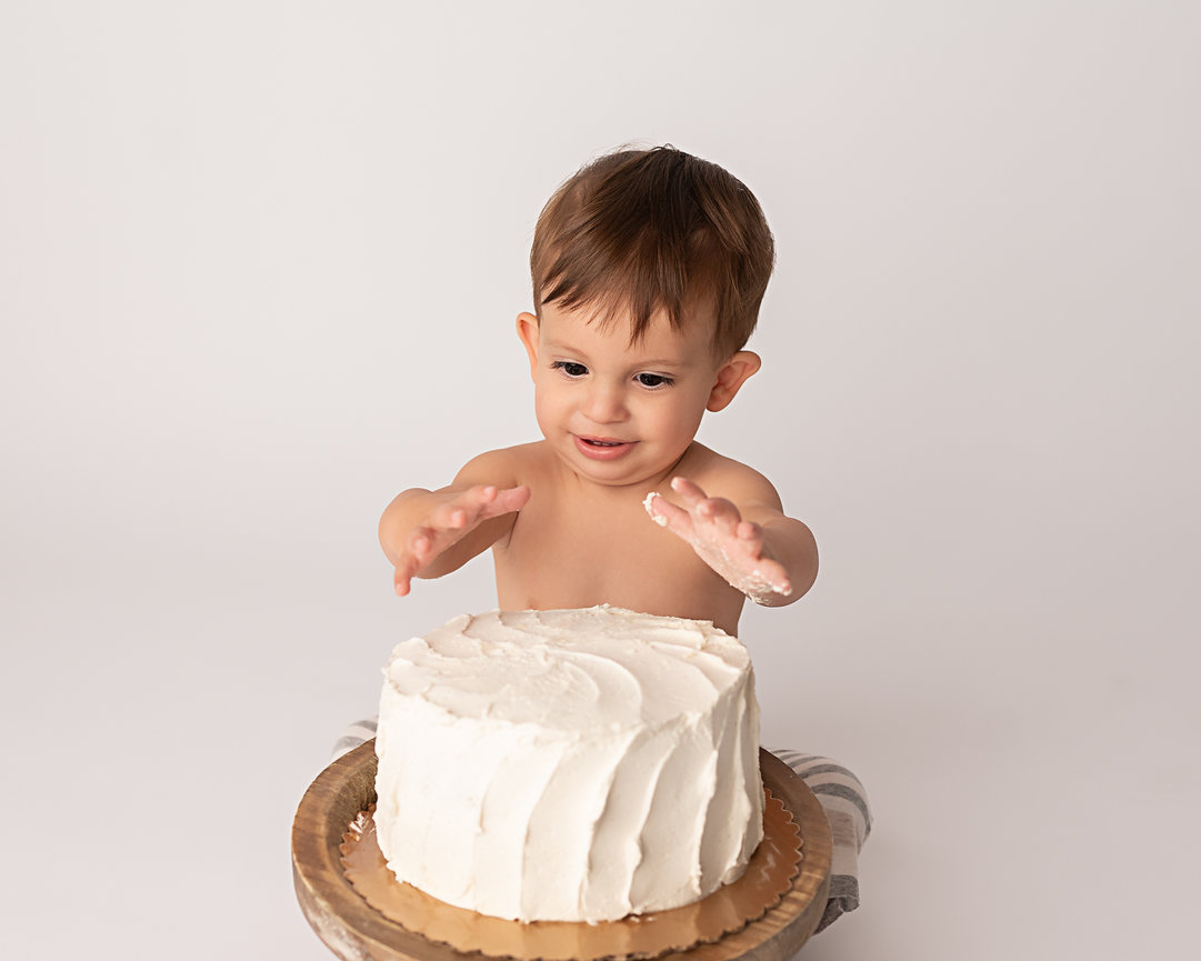 Clean portrait of baby sitting calmly before diving into cake