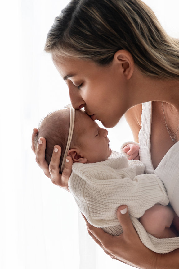 Intimate black and white moment of dad kissing baby’s forehead in Kristen Barker’s Wall Township studio