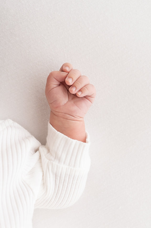 Close-up of tiny newborn fingers curled on white linen in Red Bank, NJ