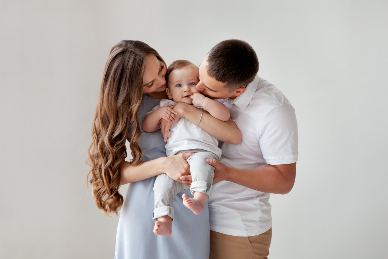 Family cuddling their baby indoors
