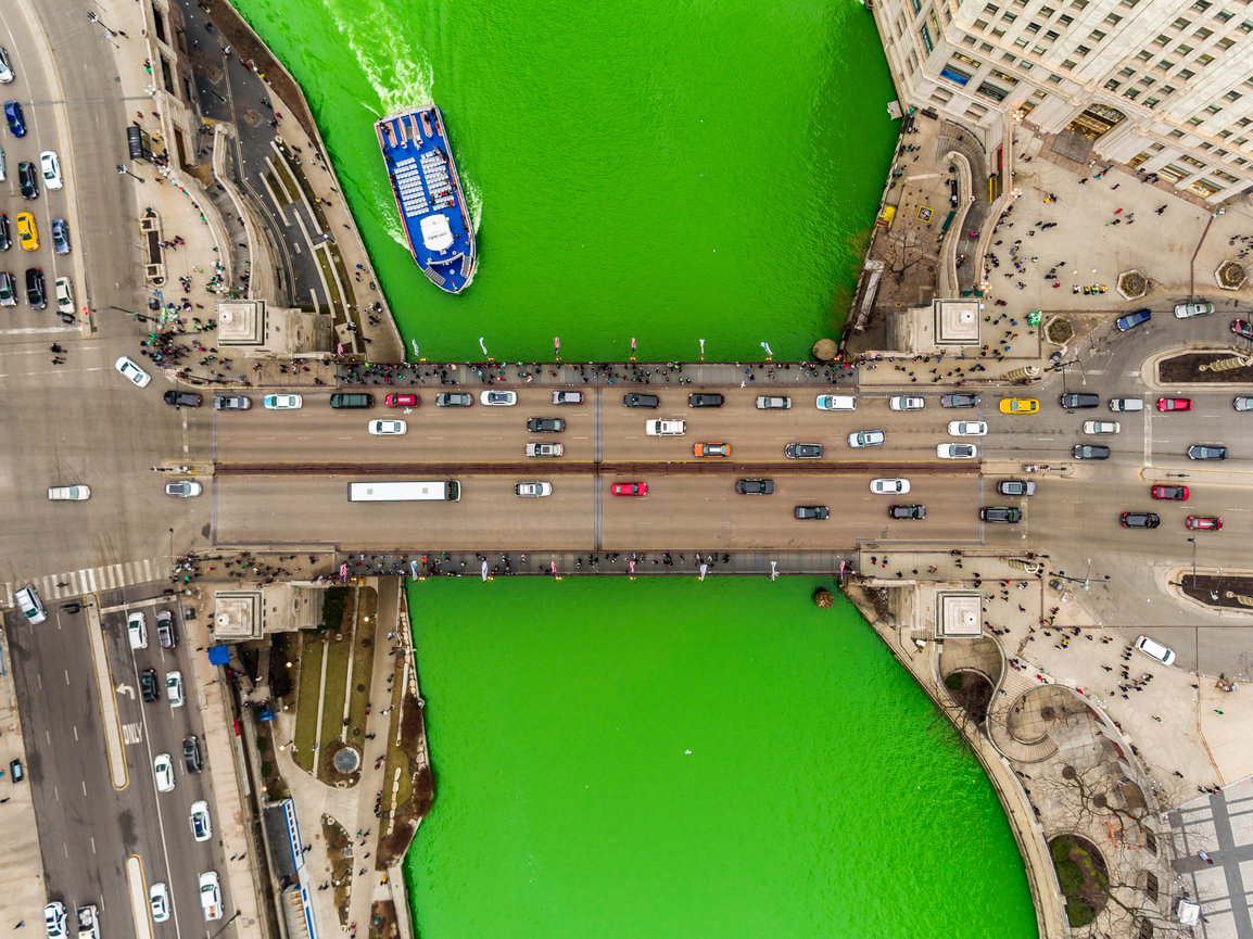 Aerial view of river dyed green with bridge traffic