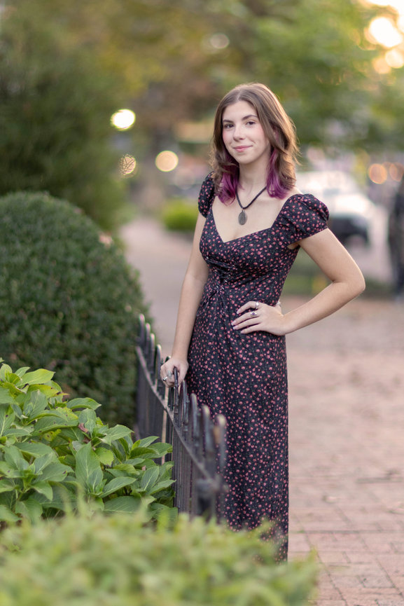 Girl in long dress standing by fence