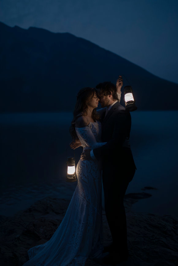 Couple holding lanterns at night by the lake