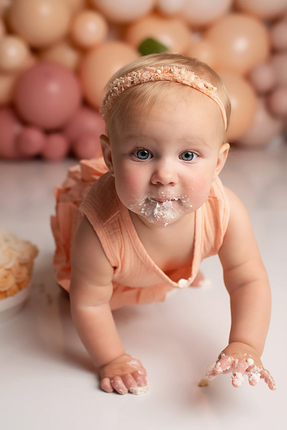baby girl eating cake during cake smash photoshoot with cake smash photographer Dreamworks Photography in Kansas City photography studio