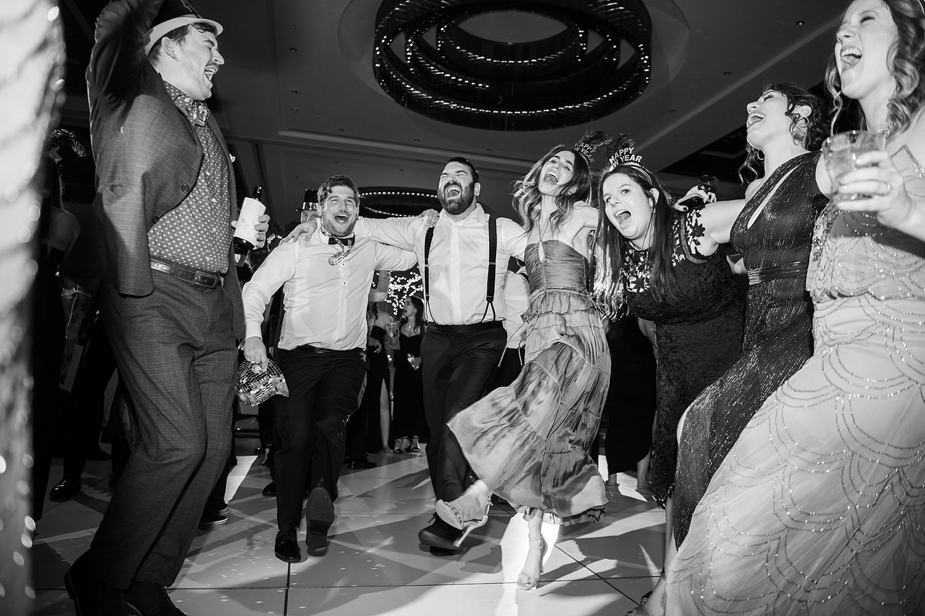 Black and white image of wedding guests dancing at reception with New Years Eve hats on. Nashville wedding photography by Heather Durham.