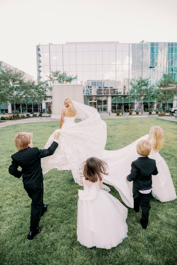 Flower girls and ring bearers holding bride's veil at Conrad Nashville. Luxury wedding photography by Heather Durham.