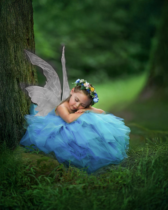 Little girl fairy in a blue gown sleeping under a tree near Cranberry Township during an outdoor fairy session