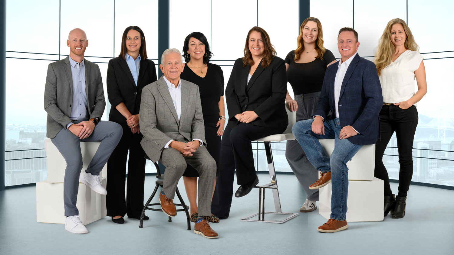 A group of eight professionally dressed people posing in a modern office setting.