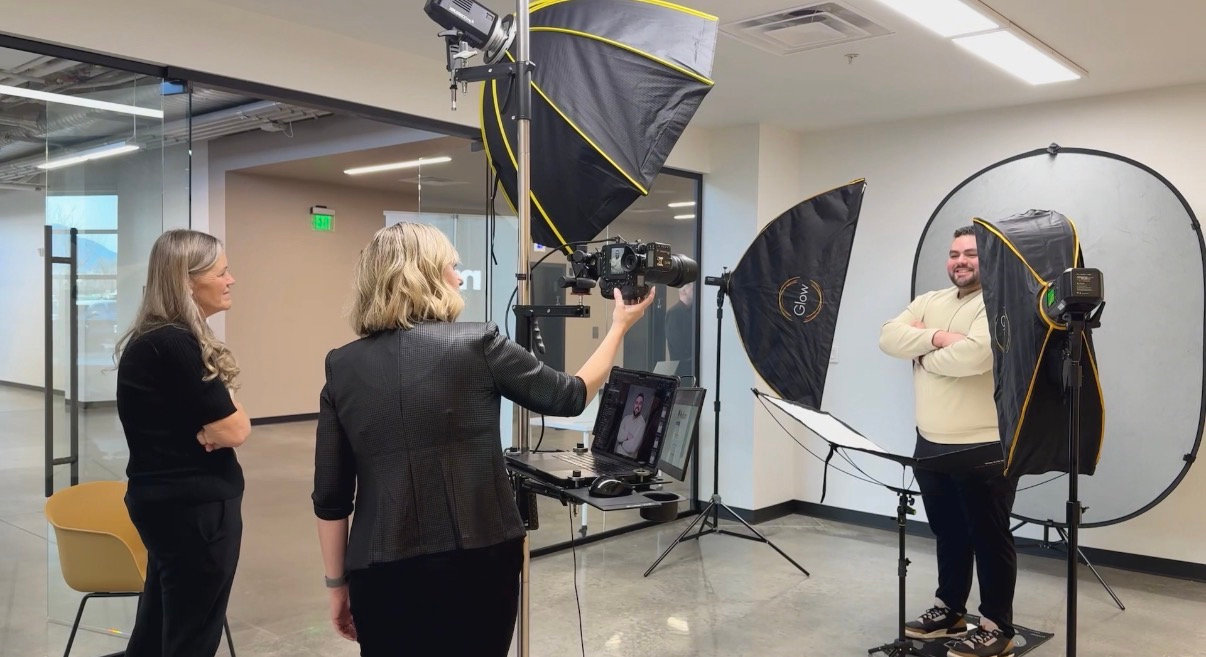 Studio portrait session with photographer, model, and lighting equipment in a white photography studio