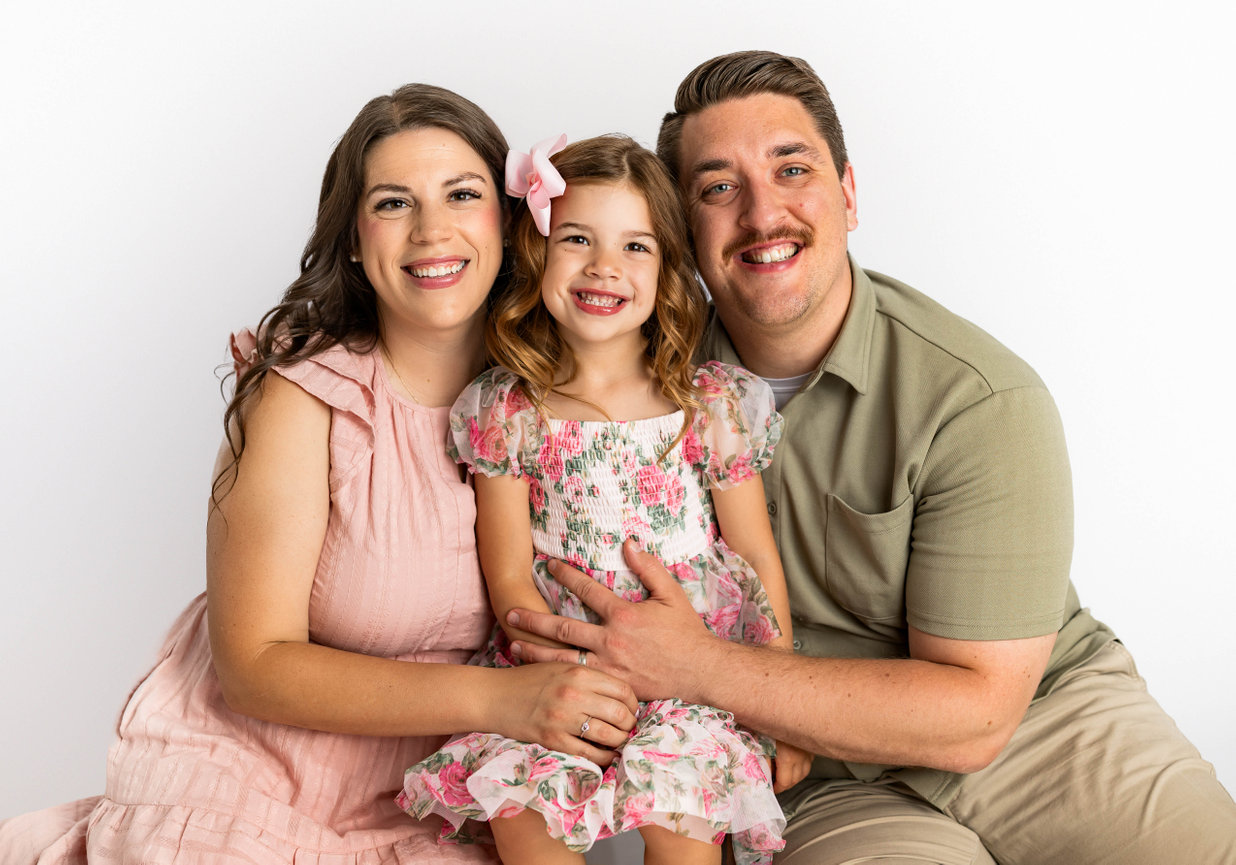 Parents cuddling both siblings on vintage bed setup in natural light studio