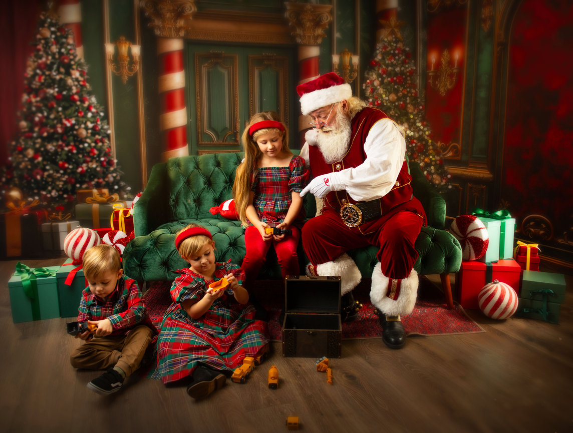 Santa sitting with children in a festive Christmas room, surrounded by gifts and decorated trees during a Baltimore Christmas mini session.