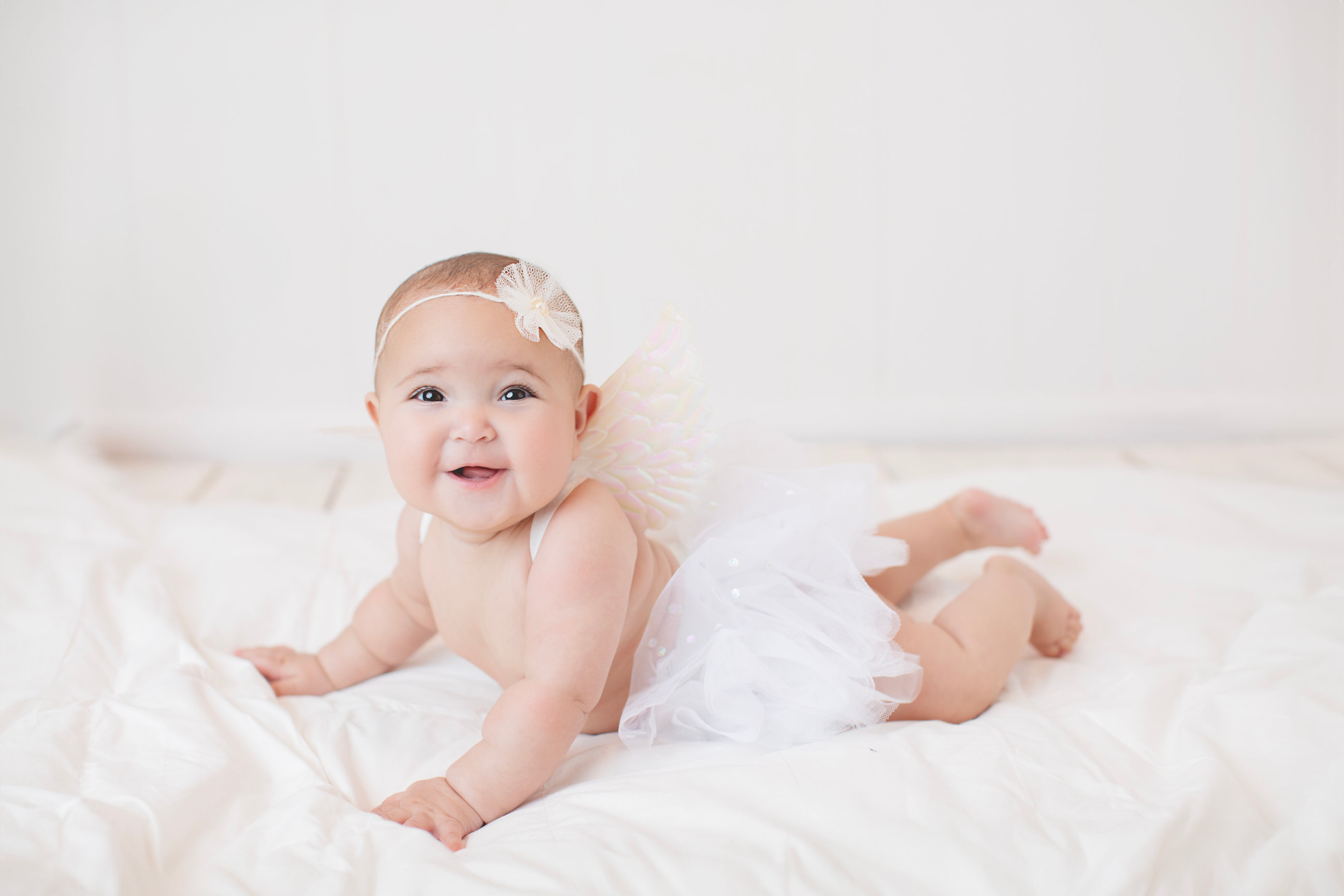 Baby enjoying tummy time on a soft white blanket