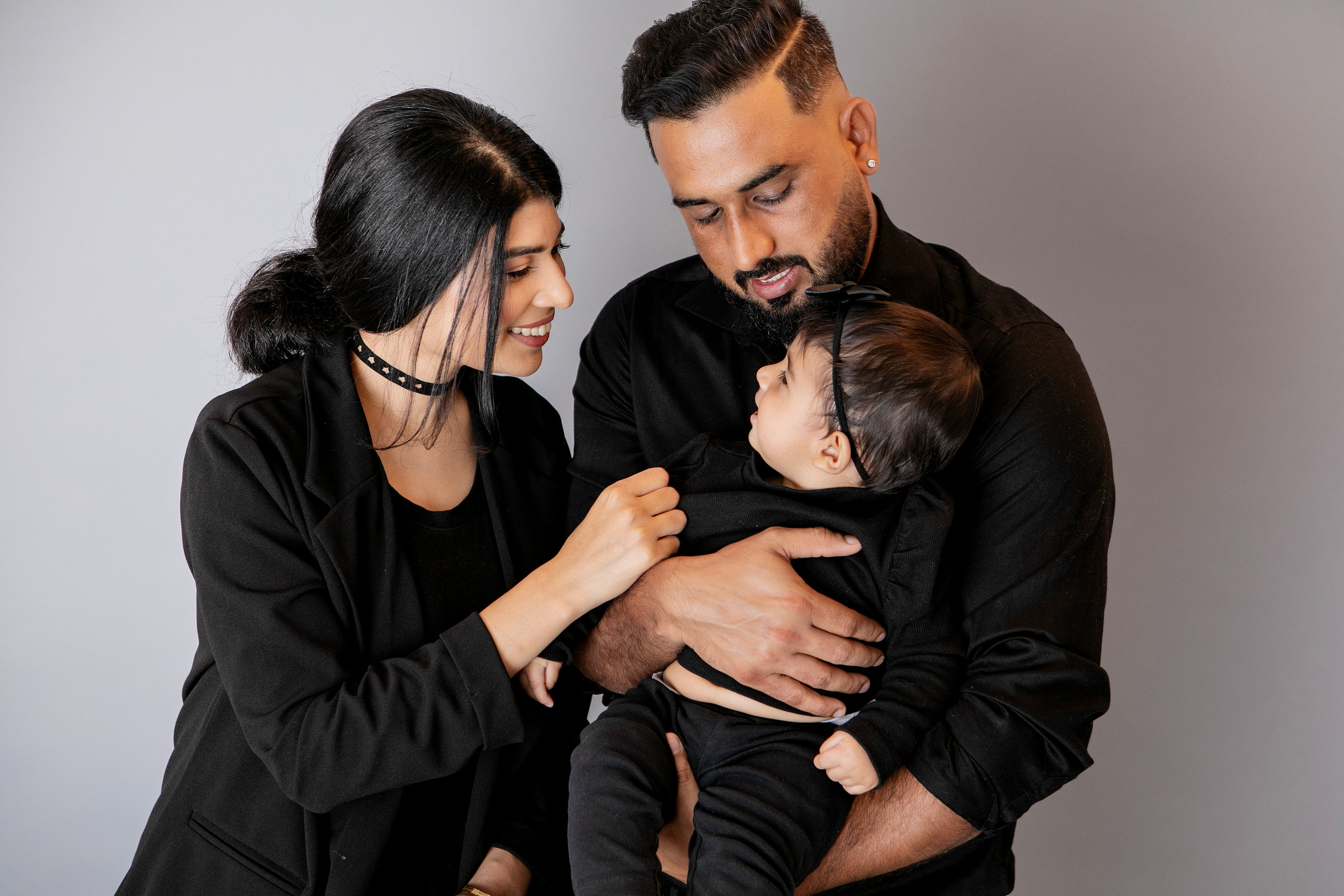 Parents in black outfits cuddling their baby