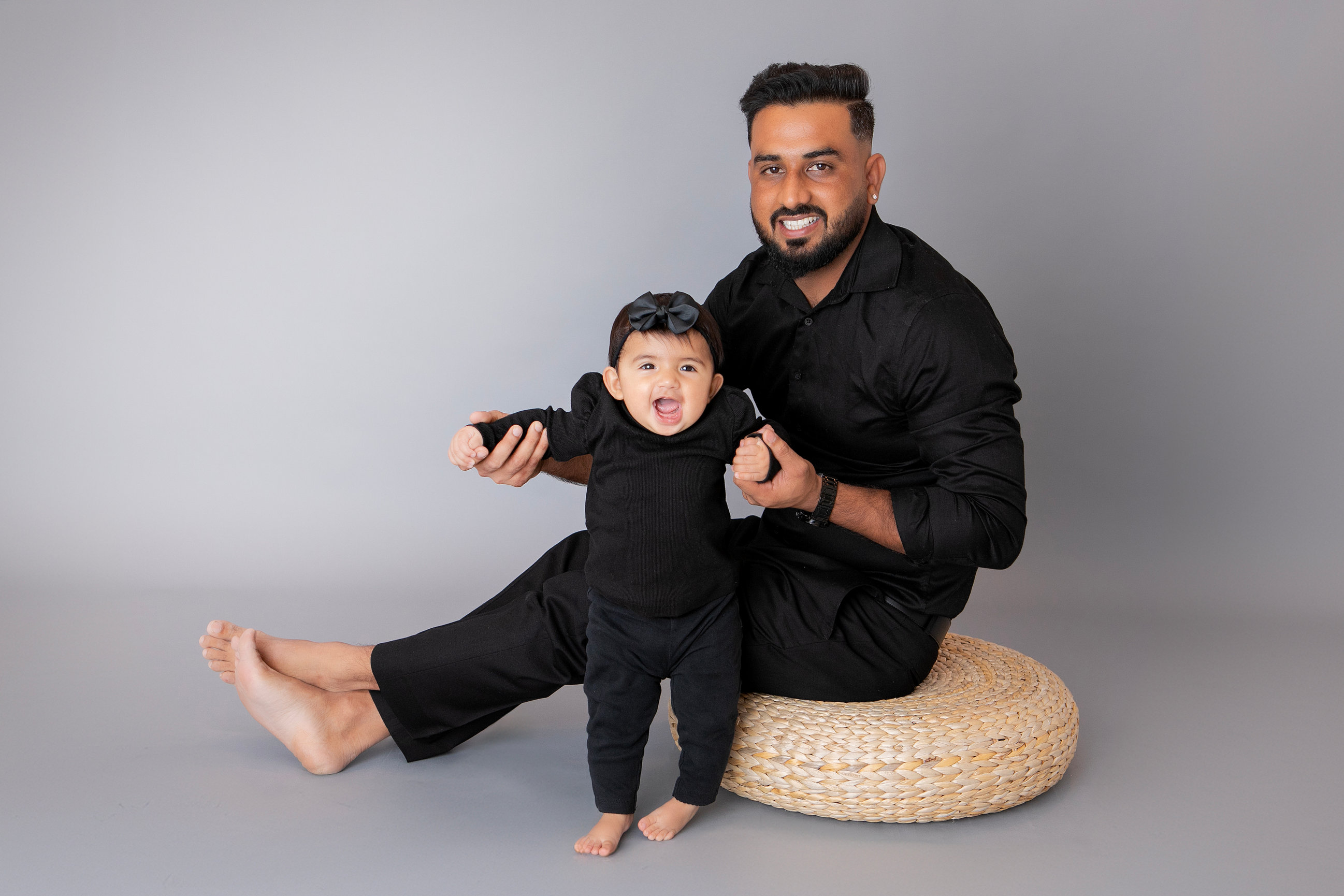 Father sitting with his baby beside a woven cushion