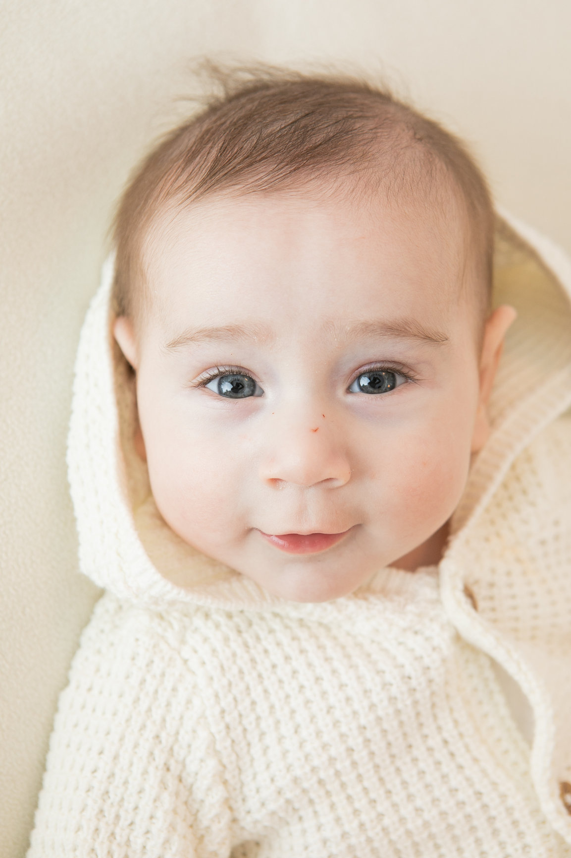 Close portrait of a baby wearing a cream knitted outfit