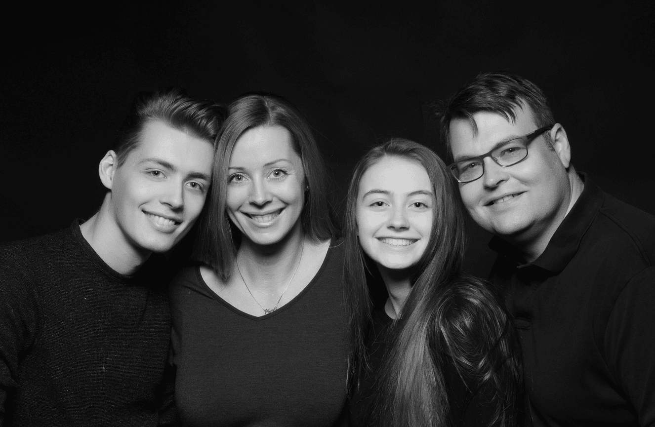 A black and white photo of a family of four with their checks pressed together in the studio of Kliks Photography in Cedar Rapids, Iowa.