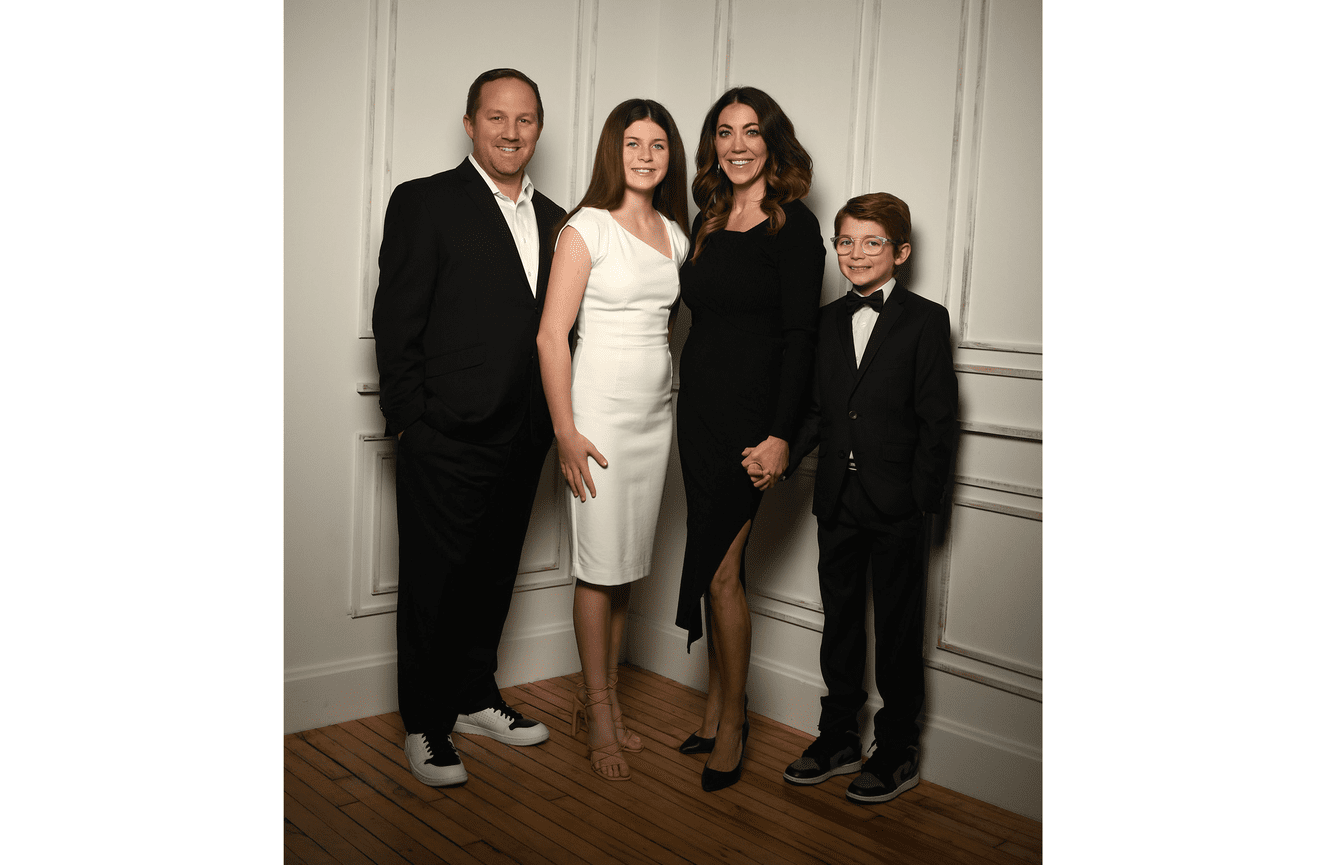Parents stand with their teenage son and daughter for a formal family photo in suits and cocktail dresses at Kliks Photography in Cedar Rapids, Iowa.