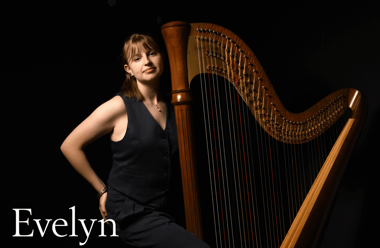 Evelyn stands next to her harp.