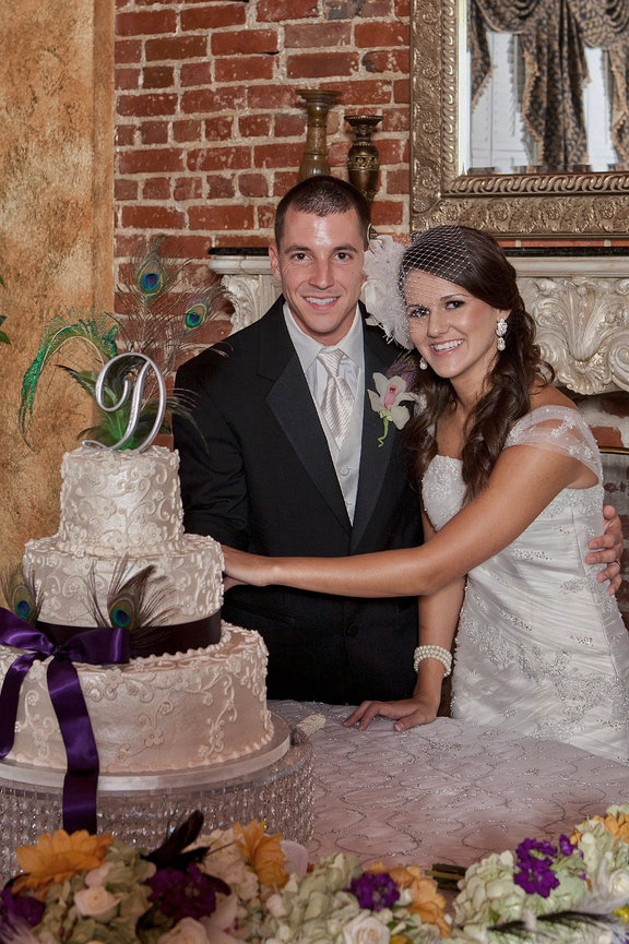 From Kiersten & Jude's reception, cutting a tiered cake with peacock feather decorations with Paul of PBM Photography.