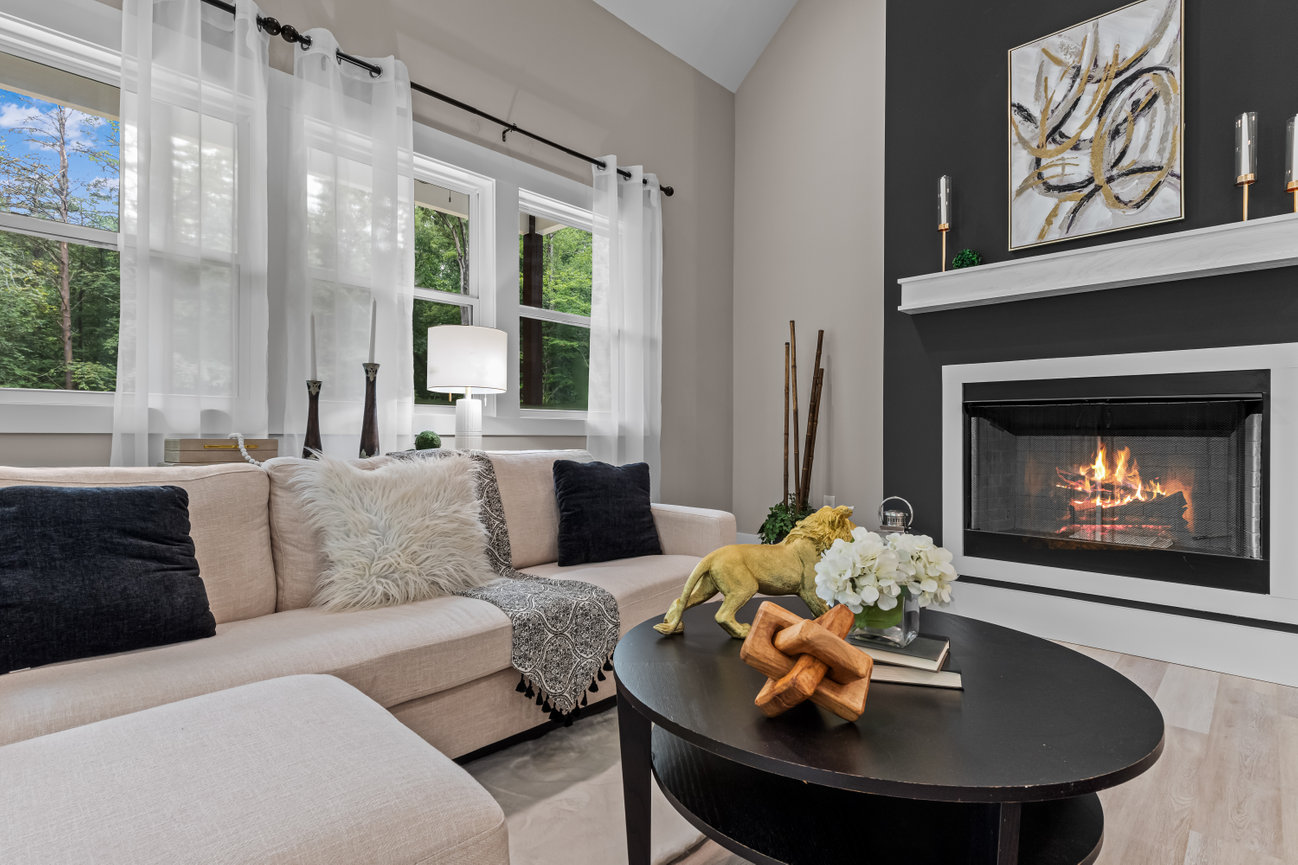 Modern living room with beige sectional, fireplace, large windows, and abstract wall art