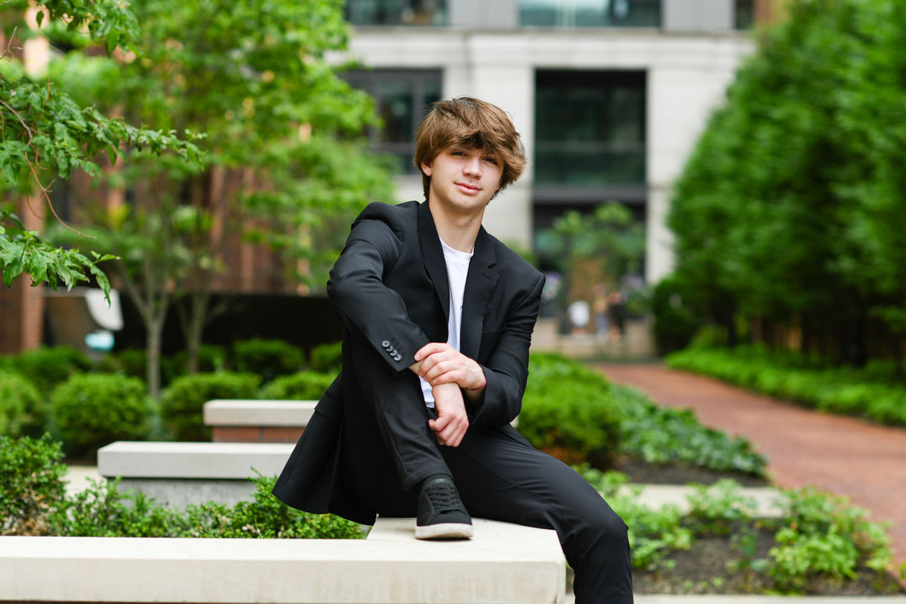 Teenage boy wearing a suit and sitting in a garden for senior pictures in Dublin OH.