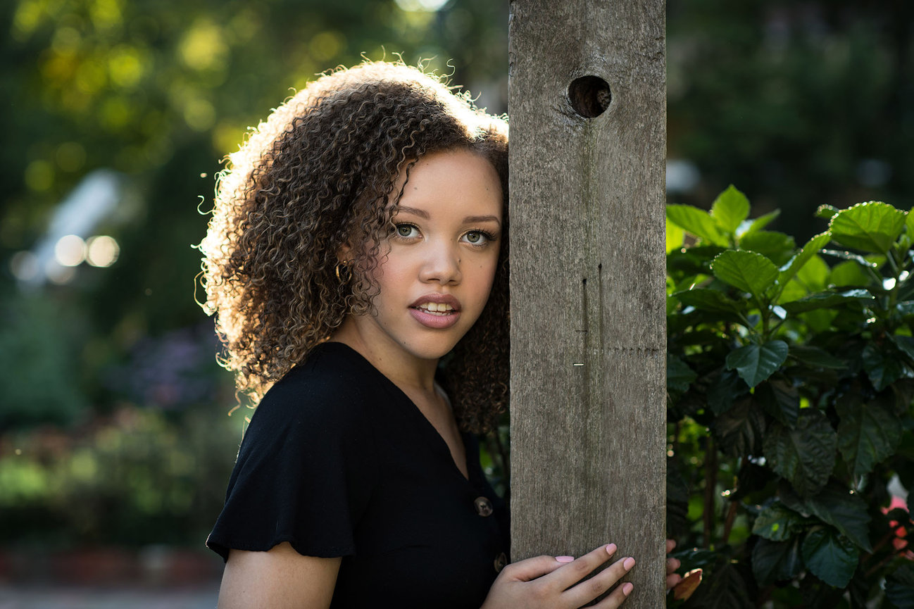high school senior girl standing next to a rustic wooden beam during outdoor senior portrait session in Dublin, Ohio