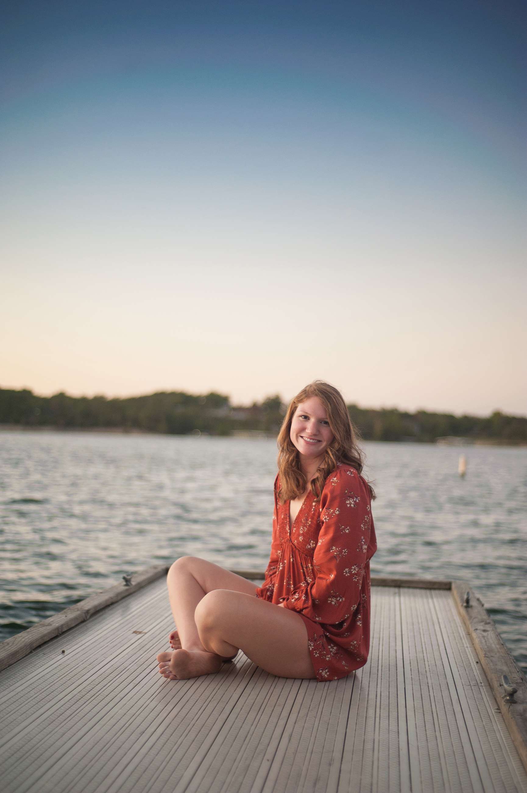 sunset portrait of senior girl sitting on dock at Table Rock Lake near Branson MO